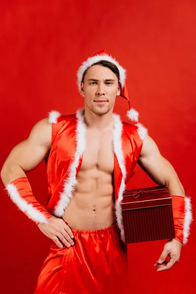 Svátky oslavy, Silvestr, Vánoce. Sexy fitness Santa Claus v klobouku je drží dárková krabička. — Stock fotografie