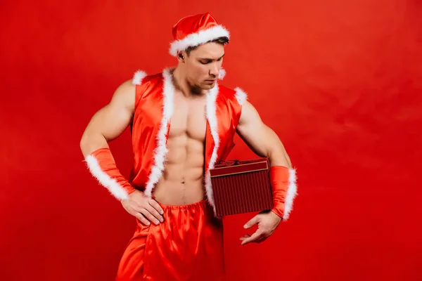 Uroczystości Święta, nowy rok, Boże Narodzenie. Fitness sexy Santa Claus w kapeluszu jest przytrzymanie pudełko. — Zdjęcie stockowe