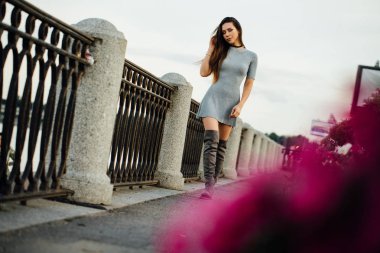 zarif seksi kız boyunca yürür. Güzel küpeşteler, sahte. Uzun saç.