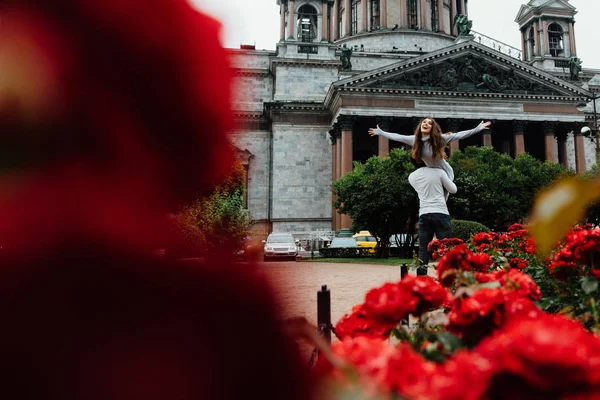 Bir arka plan, kırmızı çiçekler ve vintage mimari karşı sevgi dolu çift hugs. — Stok fotoğraf