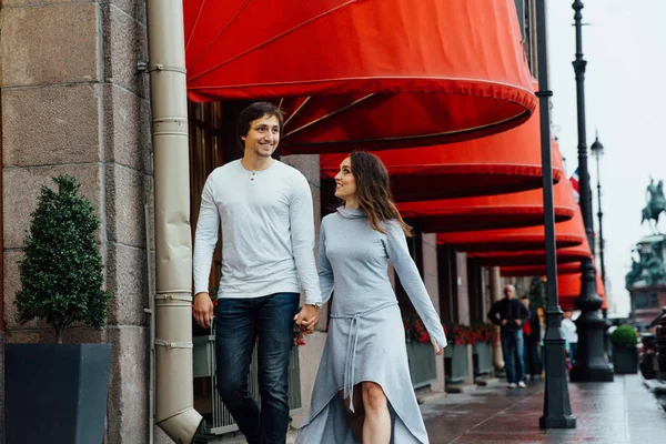 Sevgi dolu bir çift sokakta kırmızı mağaza gölgelik altında sarılmak. Kucaklama. — Stok fotoğraf