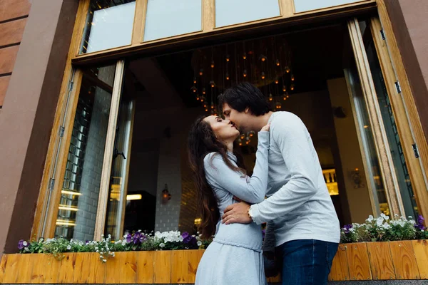 Abraços casal bonito e beijos no fundo de uma janela aberta de um café de rua na cidade . — Fotografia de Stock