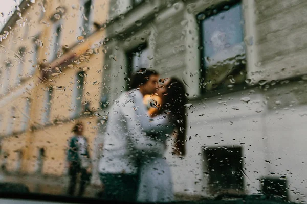 Silueta rozmazané milenci líbání na ulici města. Pohled z okna auta nebo café. — Stock fotografie