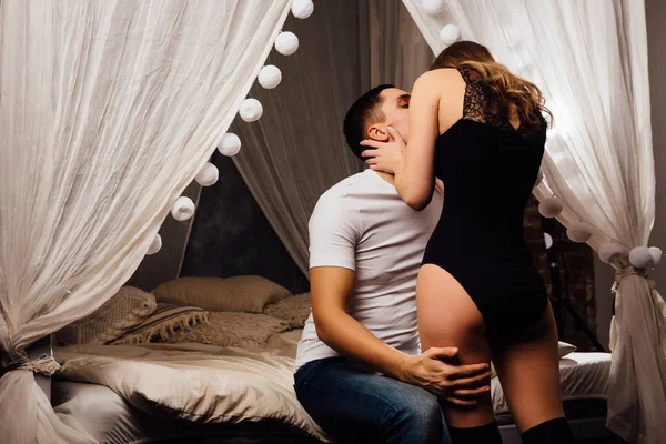 Sexy couple kissing in bed with canopy. Beautiful woman in body. — Stock Photo, Image