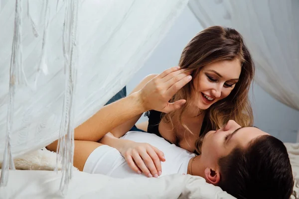 Casal sexy beijando na cama com dossel. Mulher bonita no corpo . — Fotografia de Stock