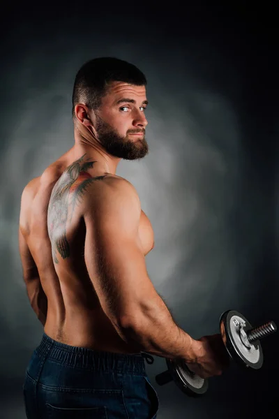 肖像的长胡须的男人健身模型，躯干。哑铃在手里，从后面。灰色背景. — 图库照片