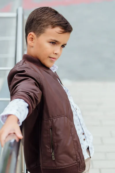 Adolescent garçon attend les escaliers à la rampe. Enfant à la mode dans des vêtements de ville élégants . — Photo