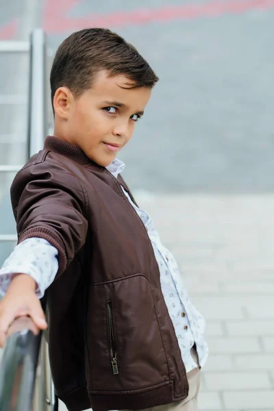 Adolescent garçon attend les escaliers à la rampe. Enfant à la mode dans des vêtements de ville élégants . — Photo