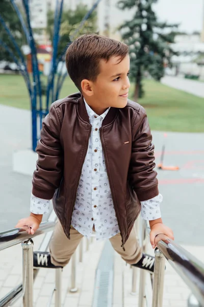 Adolescent garçon attend les escaliers à la rampe. Enfant à la mode dans des vêtements de ville élégants . — Photo