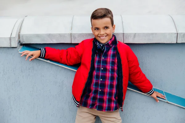 Fashion kid temps d'automne dans la ville se dresse sur le fond d'un mur de béton . — Photo