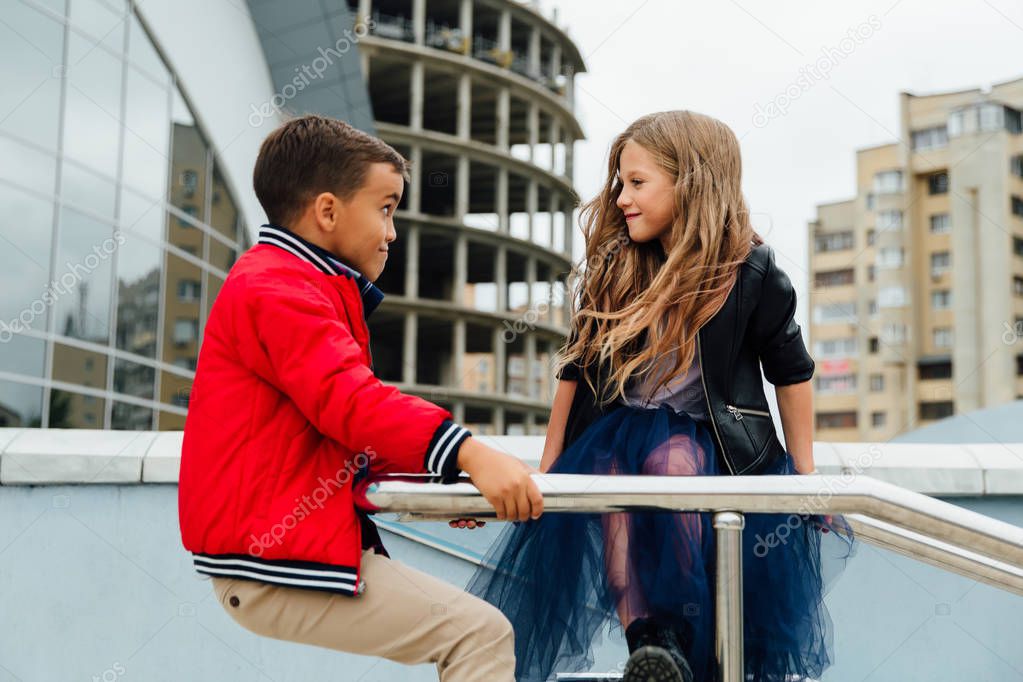 Two kids: Beautiful Children play on the railing in the street on the stairs.