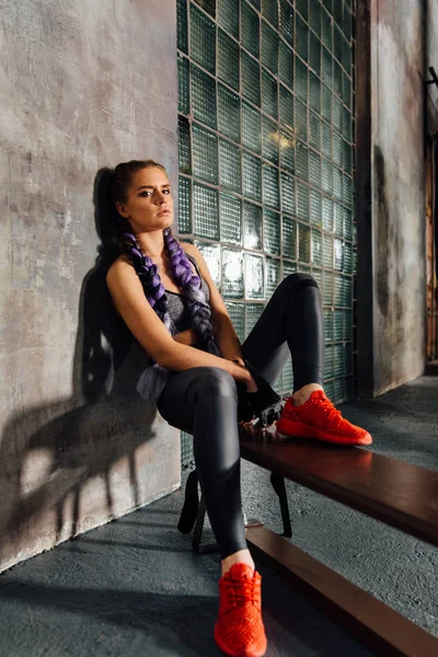 Fitness menina relaxante sentado no banco da escola de esportes depois de um treinamento de boxe duro . — Fotografia de Stock