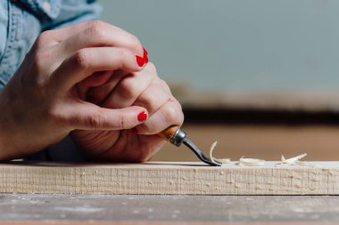 yakın çekim marangoz kadının el ile kırmızı manikür ağaç davranır, talaşı keser.