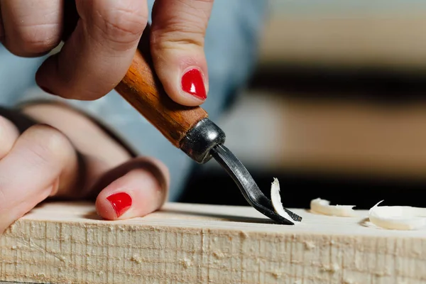 Närbild snickare kvinnans hand med en röd manikyr behandlar trädet, skär spån. — Stockfoto