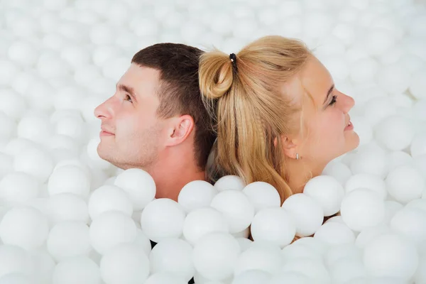 Coppia di amici amorevoli divertirsi circondati da palline di plastica bianca in una piscina asciutta . — Foto Stock