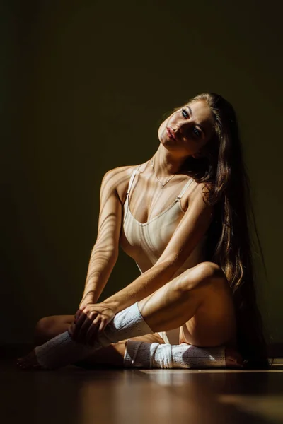 Bela dançarina moderna de balé com corpo perfeito se senta no chão no salão de estúdio . — Fotografia de Stock