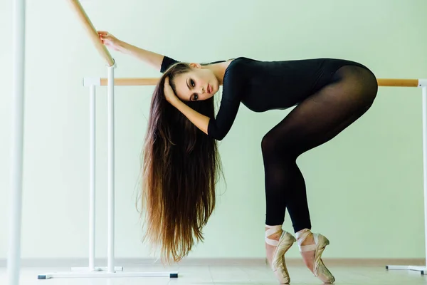 Mladé krásné tanečnice pózuje v studio wit balet baru na špičkách. Moderní sexy bruneta. — Stock fotografie