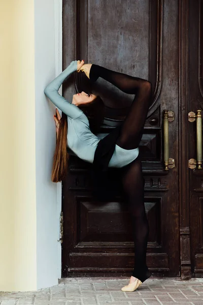 Kecses, szép lány balerina pózol az utcán, az évjárat Színház fa ajtó. — Stock Fotó