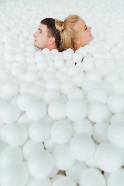 Paar liefhebbende vrienden hebben plezier omringd door witte plastic ballen in een droge zwembad. — Stockfoto