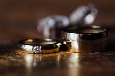 İki güzel altın alyans ve küpe ahşap arka plan üzerinde.