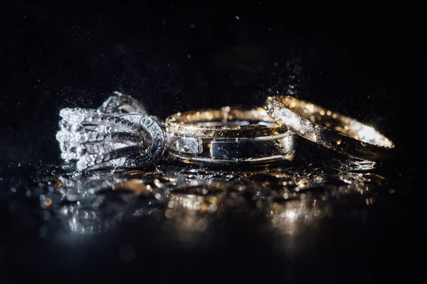 Wedding rings and earrings are wet, with drops. Reflections on the glass are professional. — Stock Photo, Image