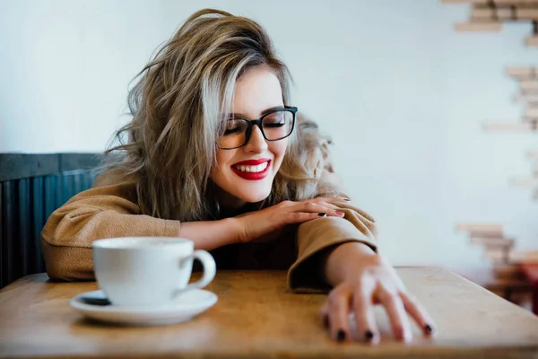 Beautiful fashionable stylish girl sits in a cafe with a cup of coffee. — Stock Photo, Image