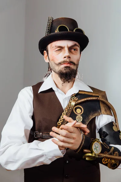 Portrait of steampunk vintage man with various mechanical devices on body.