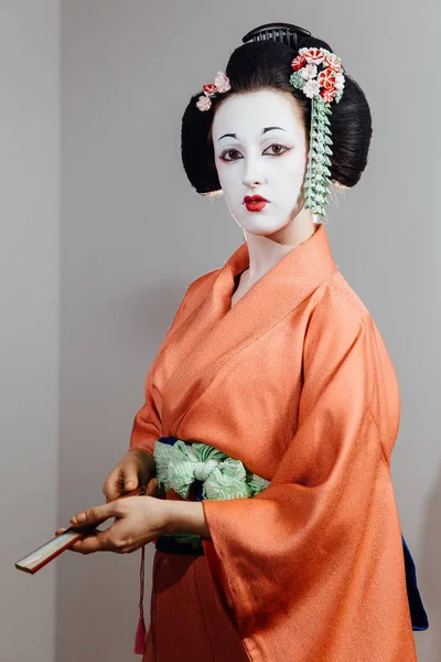 Frau in Geisha-Make-up und einem traditionellen japanischen Kimono. Studio, innen. — Stockfoto