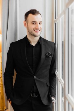 Şık genç kıl adam büyük vintage pencerenin duran ve uzakta arıyorsunuz.