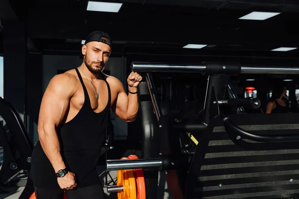 Grande fuerte hombre fitness modelo descansando en el gimnasio. apoyado en el equipo deportivo del simulador . —  Fotos de Stock