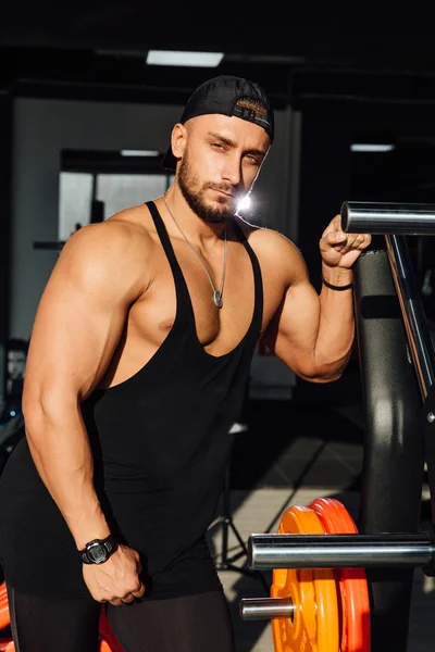 Big strong man fitness model resting in the gym. leaned against the simulator sport equipment.