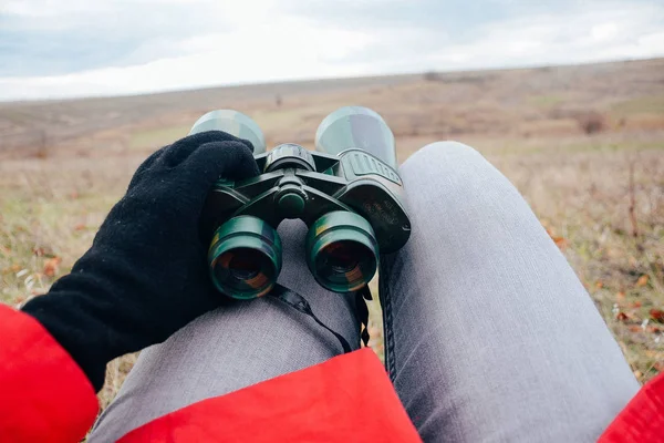 Young woman looking through binoculars on a autumn nature. Binoc