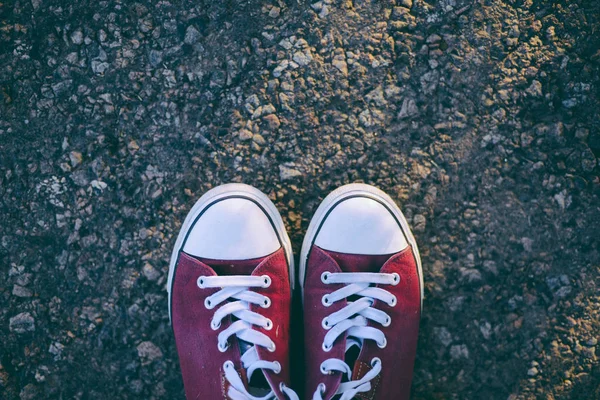 Sapatilhas na estrada. Estrada. tênis vermelhos no asfalto, vista superior . — Fotografia de Stock