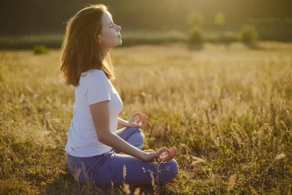 Kvinna praktiserar yoga och mediterar i lotusställning på den — Stockfoto