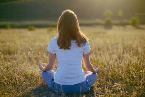 Жінка практикує йогу і медитує в позі лотоса на — стокове фото