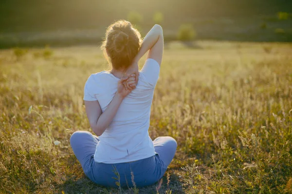 Young woman sits in namaste yoga pose with city on background. F — Stock Photo, Image