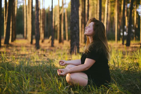 Middle aged woman sitting in lotus position in forest. her eyes — Stock Photo, Image