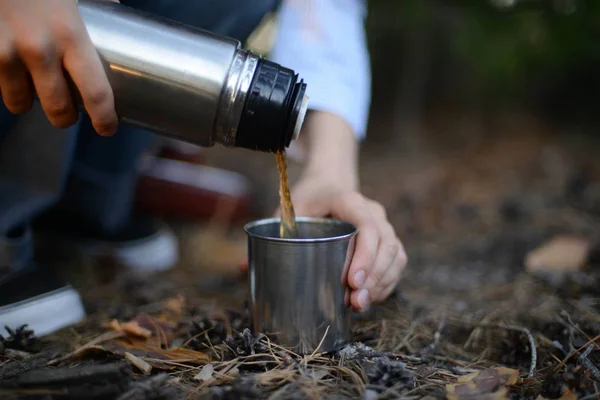 Viaggiatore ragazza versando il tè dalla tazza thermos, all'aperto. Giovane donna — Foto Stock