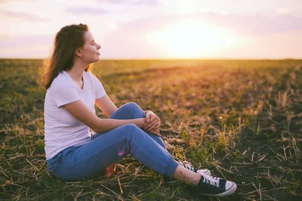 Genç kadın rahatlatıcı yaz günbatımı gökyüzü açık. İnsanlar freedo