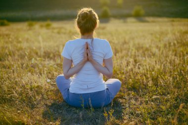 Genç kadın namaste yoga poz ile şehir arka plan üzerinde oturuyor. F