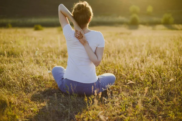 Young woman sits in namaste yoga pose with city on background. F — Stock Photo, Image