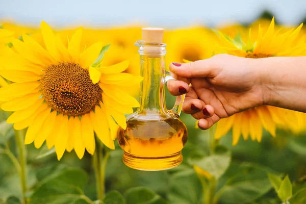 Sunflower oil in glass bottle  with sunflower field on the backg
