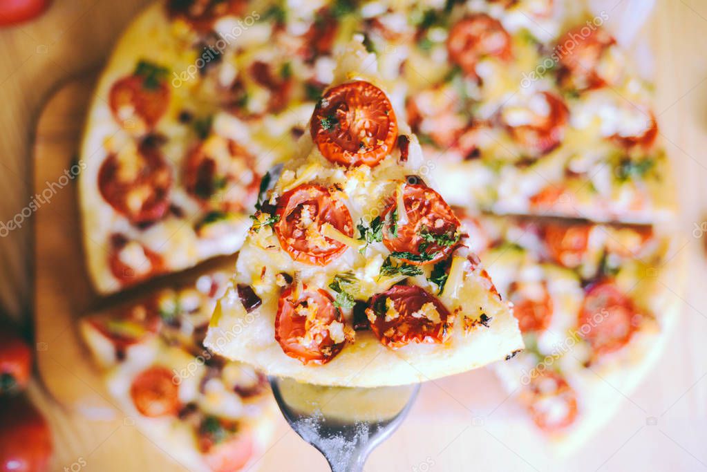  Margherita pizza with utensils and vegetable on slate plate.  Fresh pizza with tomatoes and basil on table closeup. 