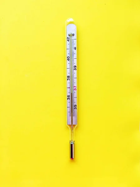 Pigułki, termometr na żółtym tle, widok z góry. — Zdjęcie stockowe