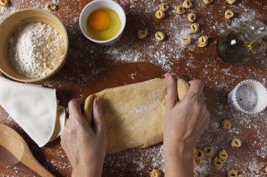 Erkek yoğurma hamur malzemelerle ahşap masa üzerinde eller