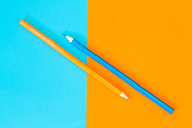 İki kalem - mavi ve sarı renkli kağıt üzerinde turuncu ve cyan.. 