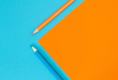 İki kalem - mavi ve sarı renkli kağıt üzerinde turuncu ve cyan.. 