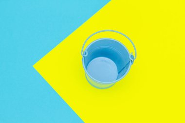 Renkli kağıtların üzerindeki mavi boş metal kova.. 