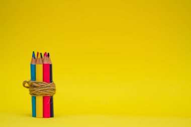 Sarı arka planda renkli kalemler. Yazıtlar için boş bir yer. İple bağlanmış kalemler.