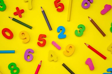 Parlak renkli, sarı arka planda ahşap numaralar. Matematiksel elementler ve semboller. Yukarıdan bak. Bir kartpostal için ilginç bir okul geçmişi..